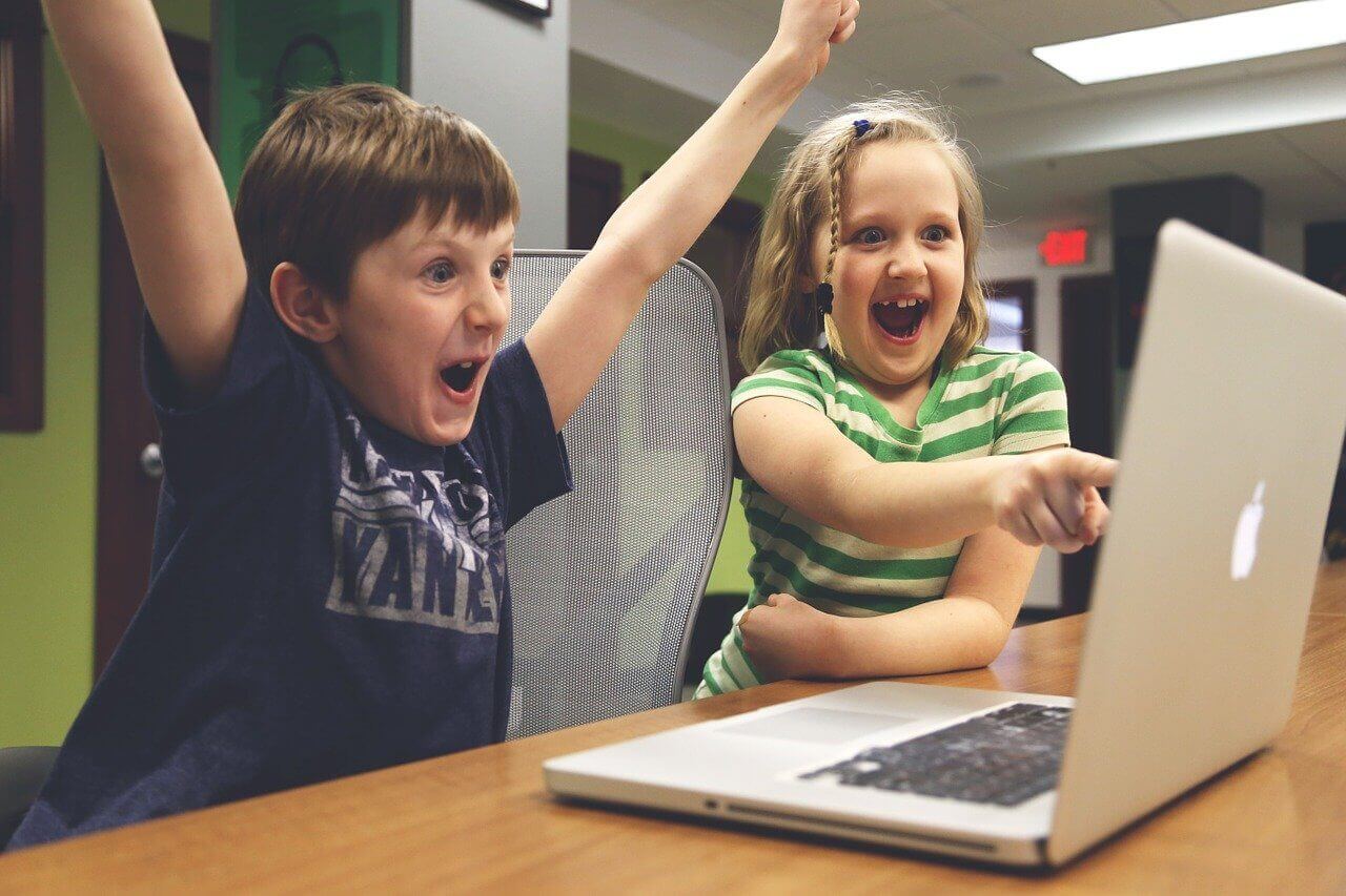 Image of two kids playing video games in front of a computer