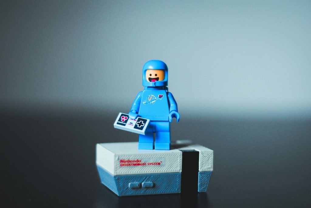 A vintage Nintendo gaming console, compact in size, with a Lego brick placed on top, representing a playful and creative combination of old and new.