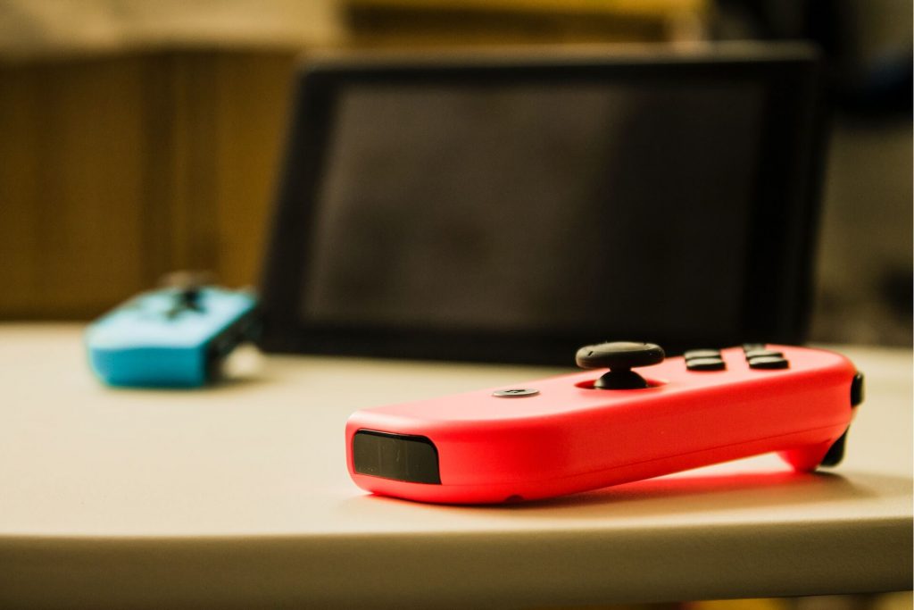 A Nintendo Switch gaming console, featuring a handheld screen with detachable controllers on the sides and a dock for playing on a TV, providing versatile gaming experiences.